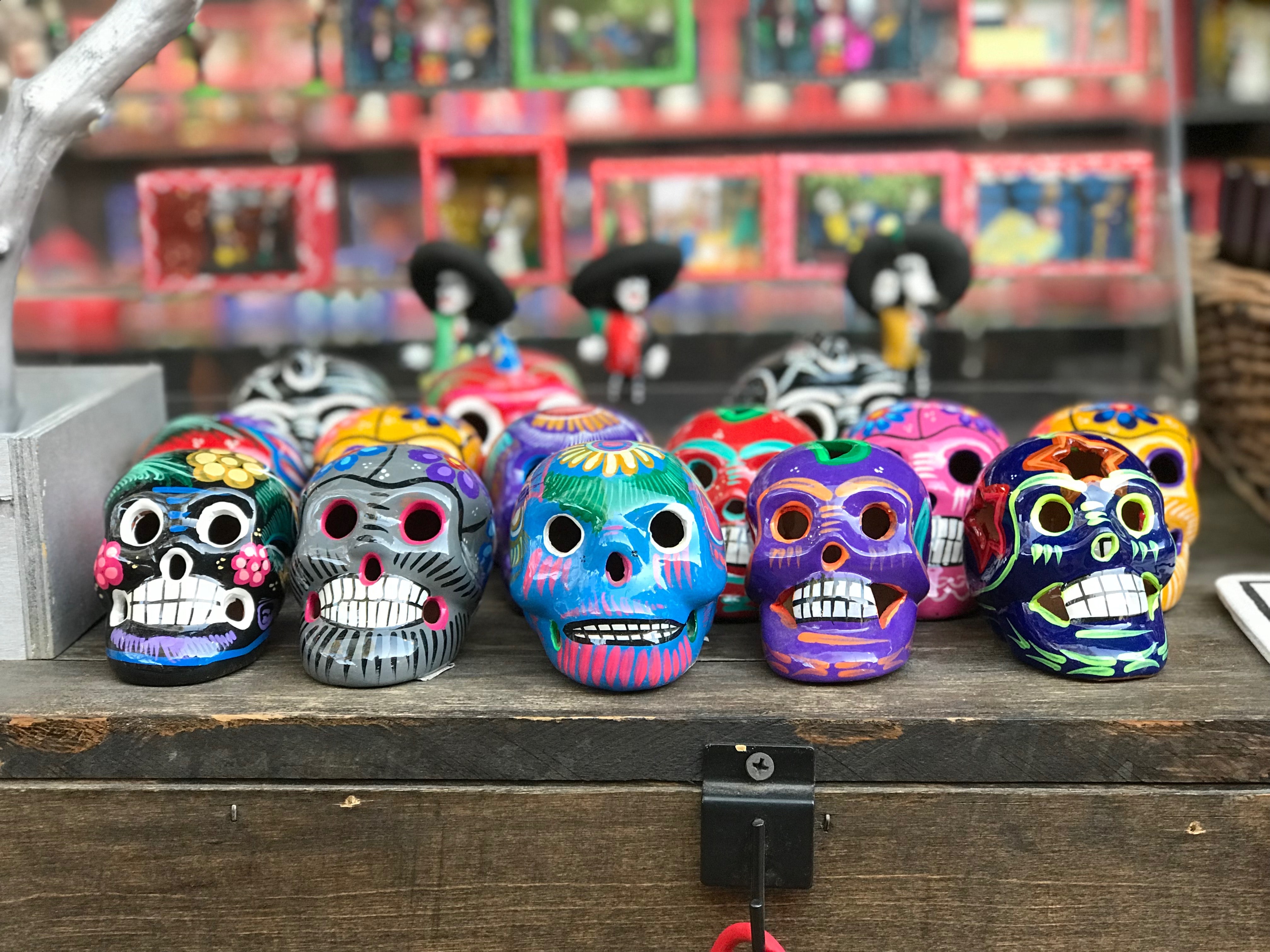 Brightly colored miniature skull figurines sit atop a wooden box.