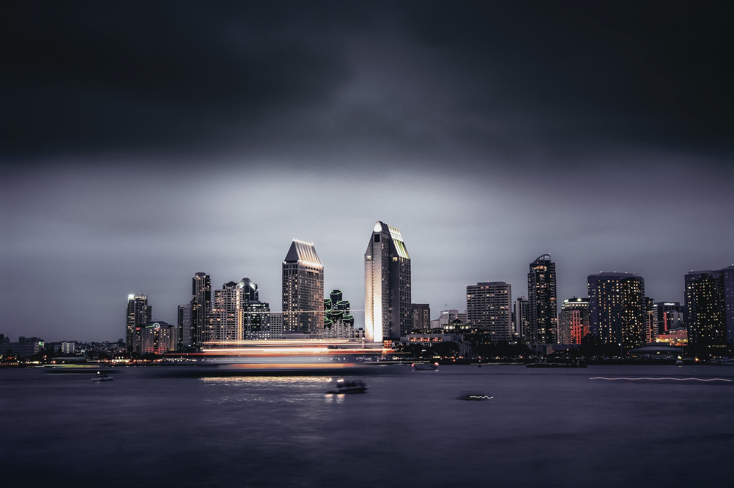 San Diego's downtown skyline is shown at night with motion-blurred objects appearing on the water